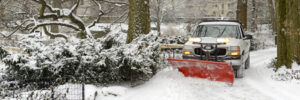 snow plow truck clearing driveway of snow