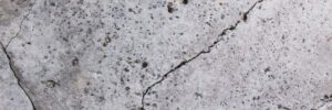 Cracked concrete surface with visible small holes and rough texture.