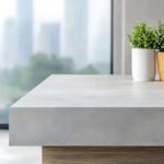 A gray concrete countertop with two potted plants sits in front of large windows overlooking a cityscape.